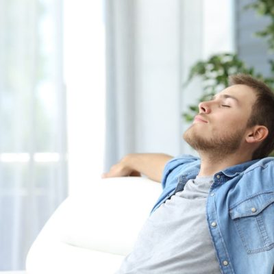 Portrait of a casual tired man resting sitting on a couch at home